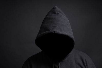 Person in hooded shirt against black background