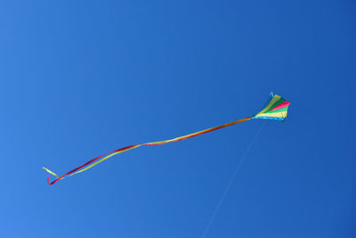 Low angle view of kite flying against clear blue sky