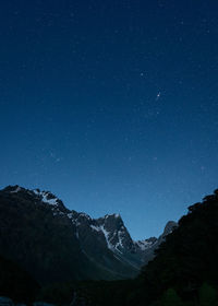 Scenic view of mountains against blue starry sky at night