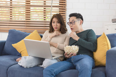 Young woman using mobile phone while sitting on sofa