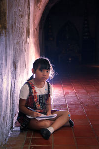 Portrait of girl studying while sitting in corridor