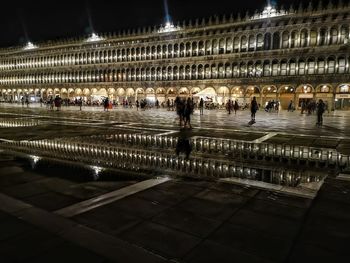 Group of people walking in illuminated building at night