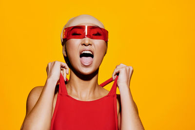 Portrait of young woman against yellow background