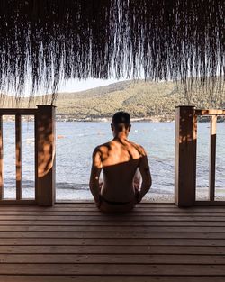 Rear view of shirtless man sitting in gazebo