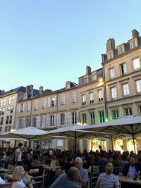 Group of people in city against clear blue sky