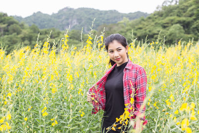 Portrait of smiling young woman standing on field