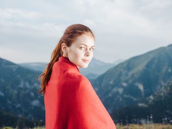 Portrait of young woman standing against mountains