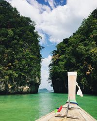 Cropped image of longtail boat on sea against mountains