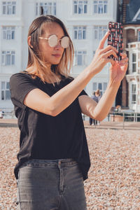 Asian woman taking photos with her phone on the beach