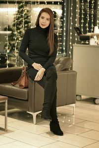 Full length portrait of woman sitting on armchair