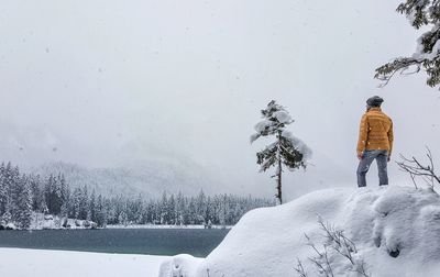 Man standing on snowy rock against sky