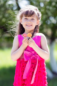 Portrait of smiling girl holding lollipops in park