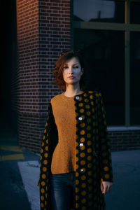 Portrait of woman standing against brick wall