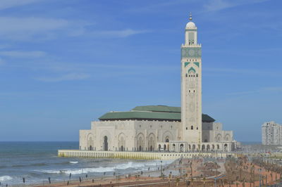 Historic building by sea against blue sky