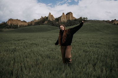 Rear view of woman standing on grassy field against sky