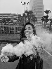 Portrait of smiling young woman standing against building