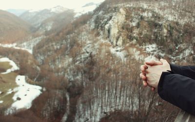 Close-up of man holding hands against mountain