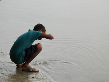 Rear view of boy sitting at beach