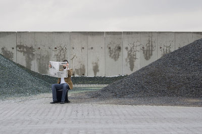 Man holding newspaper against wall