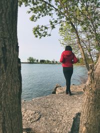 Rear view of woman standing by lake