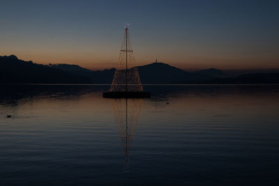 Silhouette sailboat on lake against sky during sunset