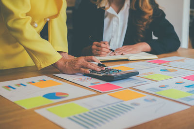 Midsection of businesswomen discussing over documents in office