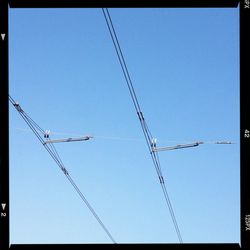 Low angle view of electricity pylon against blue sky