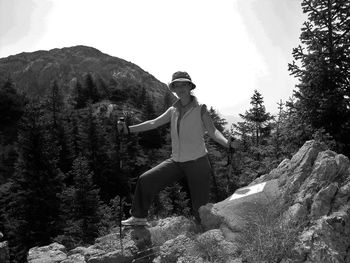 Portrait of smiling woman standing on rocks against mountain