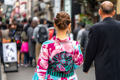 Rear view of people walking on street in city