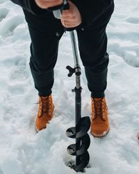 Low section of man standing on snow field