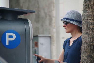 Midsection of woman wearing hat at atm