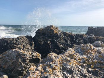 Scenic view of rocks on beach against sky