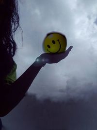 Close-up of hand holding toy against sky