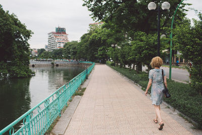 Rear view of woman walking on bridge in city