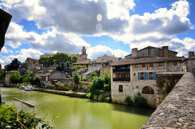 Panoramic view of buildings by river against cloudy sky