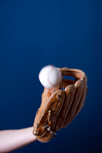 Close-up of hand holding bubble against blue background