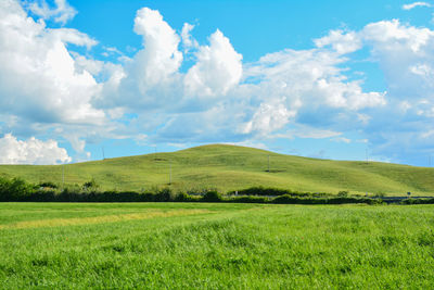 Scenic view of green landscape against cloudy sky