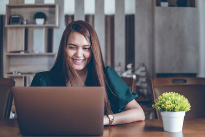 Young woman using phone while sitting on table