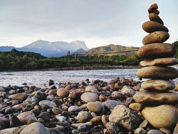 Stack of pebbles in lake against sky