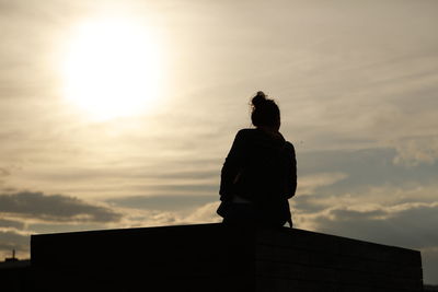 Silhouette man standing by building against sky during sunset