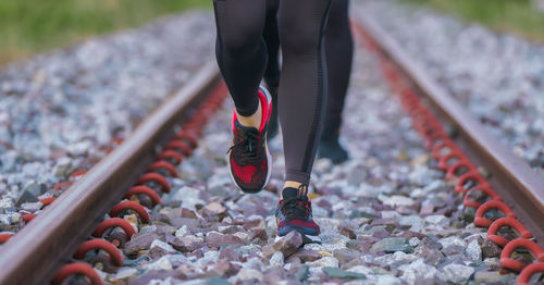 Low section of woman running on railroad track