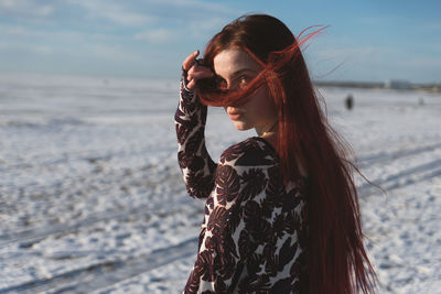 Portrait of woman standing at beach against sky