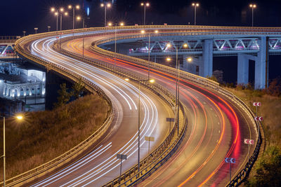 Highway at night lights. fast car light path, trails and streaks on interchange bridge road. night