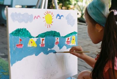 Close-up of girl painting on canvas outdoors