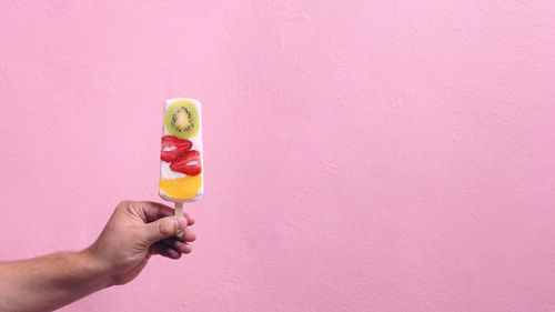 Hand holding ice cream against wall