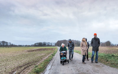 Family walking on dirt road amidst field