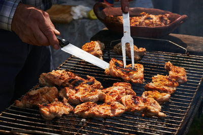 Midsection of man preparing food on barbecue grill