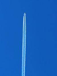 Low angle view of airplane flying against clear blue sky