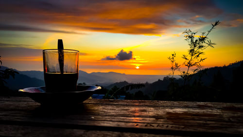 Glass of table against sky during sunset