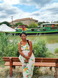 Portrait of young woman standing against lake